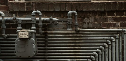 Stalowe rury i gazomierz na ceglanej ścianie w stylu industrialnym