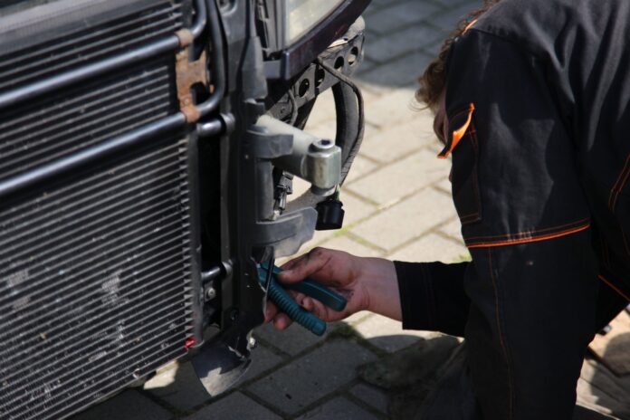 Mechanik naprawiający chłodnicę samochodową na zewnątrz